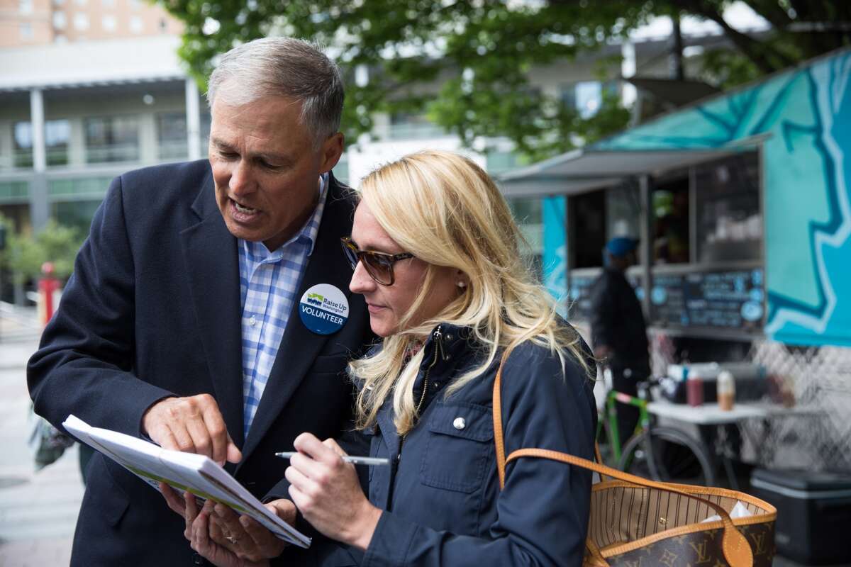 Governor Jay Inslee instructs Jennifer Garvale on how to sign in support of Initiative 1433, a campaign to raise the statewide minimum wage to $13.50.  The Democrats have latched onto the minimum wage initiative as a way of boosting the November vote.
