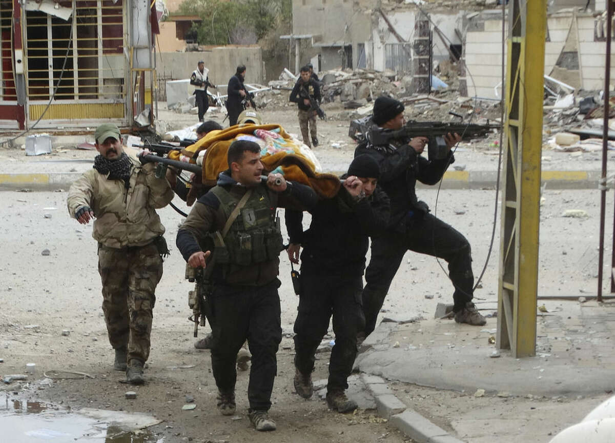 In this Monday, Jan. 4, 2016, photo, Iraqi security forces and allied Sunni tribal fighters evacuate an injured woman after she was shot by Islamic State group fighters as she tried to cross from neighborhoods under control of Islamic State group to neighborhoods under control of Iraqi security forces in Ramadi, 70 miles (115 kilometers) west of Baghdad, Iraq. Islamic State extremists had captured Ramadi in May, in one of its biggest advances since the U.S.-led coalition began striking the group in 2014. Recapturing the city, which is the provincial capital of Anbar, provided a major morale boost for Iraqi forces. (AP Photo)