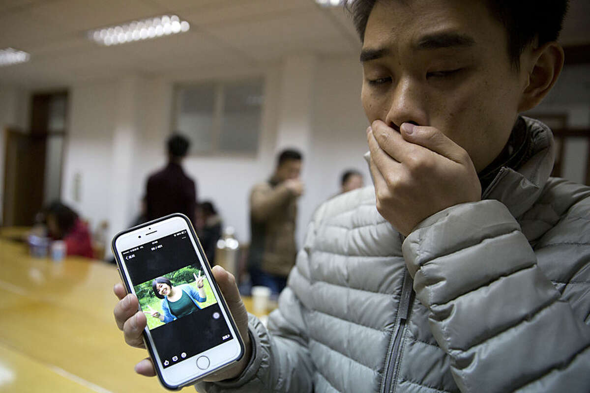 A man who only gave his surname Zhao shows a photo of his girlfriend Pan Haiqin who was killed in the deadly stampede in Shanghai, China, Friday, Jan. 2, 2015. People unable to contact friends and relatives streamed into hospitals Thursday, anxious for information after a stampede during New Year's celebrations in Shanghai's historic waterfront area killed 36 people in the worst disaster to hit one of China's showcase cities in recent years. (AP Photo/Ng Han Guan)