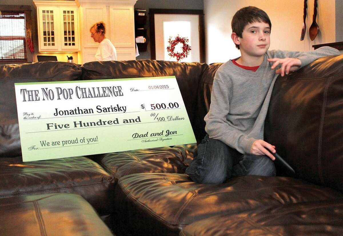 Jonathan Sarisky, 11, poses Dec. 24, 2014, in Livingston, Mont., with the big check he received from his parents for successfully completing the “No Pop Challenge,” in which Jon, as he likes to be called, avoided all sugary beverages for one year. Per the contract detailing the terms of the challenge, Jonathan is free to spend the $500 however he chooses. (AP Photo/Livingston Enterprise, Hunter D'Antuono)