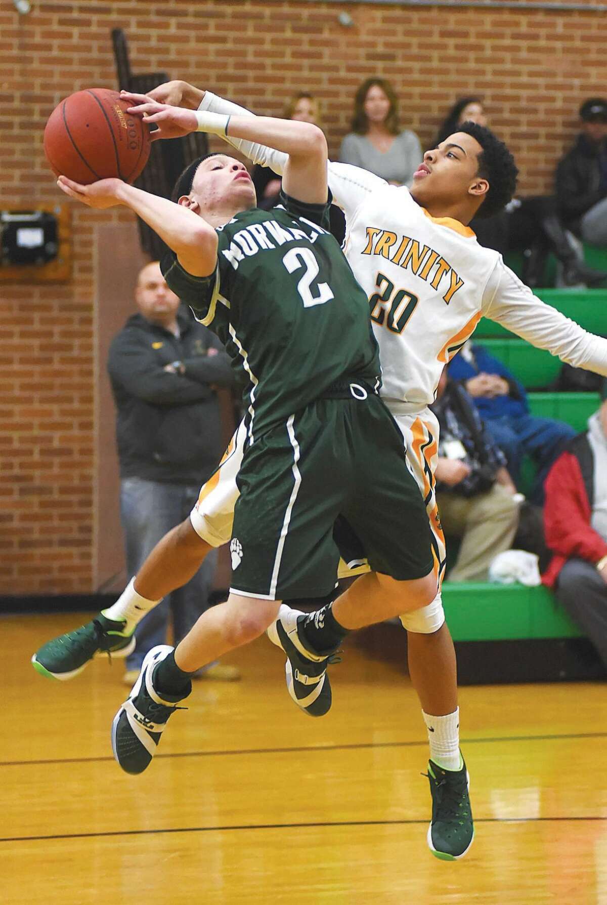 Hour photo/John Nash - Norwalk's Mark Crafter Jr. (2) gets fouled by Trinity Catholic's Cameron Blake during the first half of Tuesday's FCIAC boys basketball game at Walsh Court in Stamford.