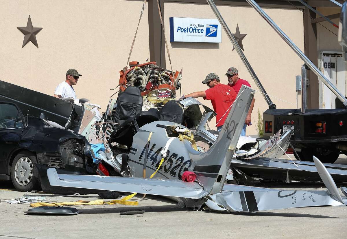 On Friday, June 10, 2016, a crew works to remove the wreckage of a small plane from a parking lot where it crashed Thursday killing three people, in Houston.