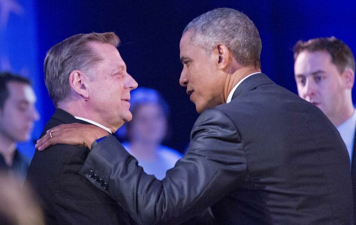 President Barack Obama, right, stops to greet Father Michael Pfleger, left, Pastor at Saint Sabina Catholic Church in Chicago during a commercial break at a CNN televised town hall meeting at George Mason University in Fairfax, Va., Thursday, Jan. 7, 2016. Obama's proposals to tighten gun controls rules may not accomplish his goal of keeping guns out of the hands of would-be criminals and those who aren't legally allowed to buy a weapon. In short, that's because the conditions he is changing by executive action are murkier than he made them out to be. (AP Photo/Pablo Martinez Monsivais)