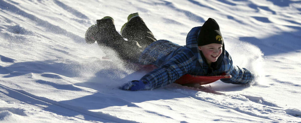 FILE - In this Dec. 11, 2013 file photo Zoe Reisen,10, of Dubuque, Iowa, sleds down a hill at Allison-Henderson Park on in Dubuque, Iowa. Faced with the potential bills from people who are injured sledding, Dubuque is one of the cities across the country the is opting to close hills rather than face the risk of large liability claims. (AP Photo/The Telegraph Herald, Jessica Reilly, File)