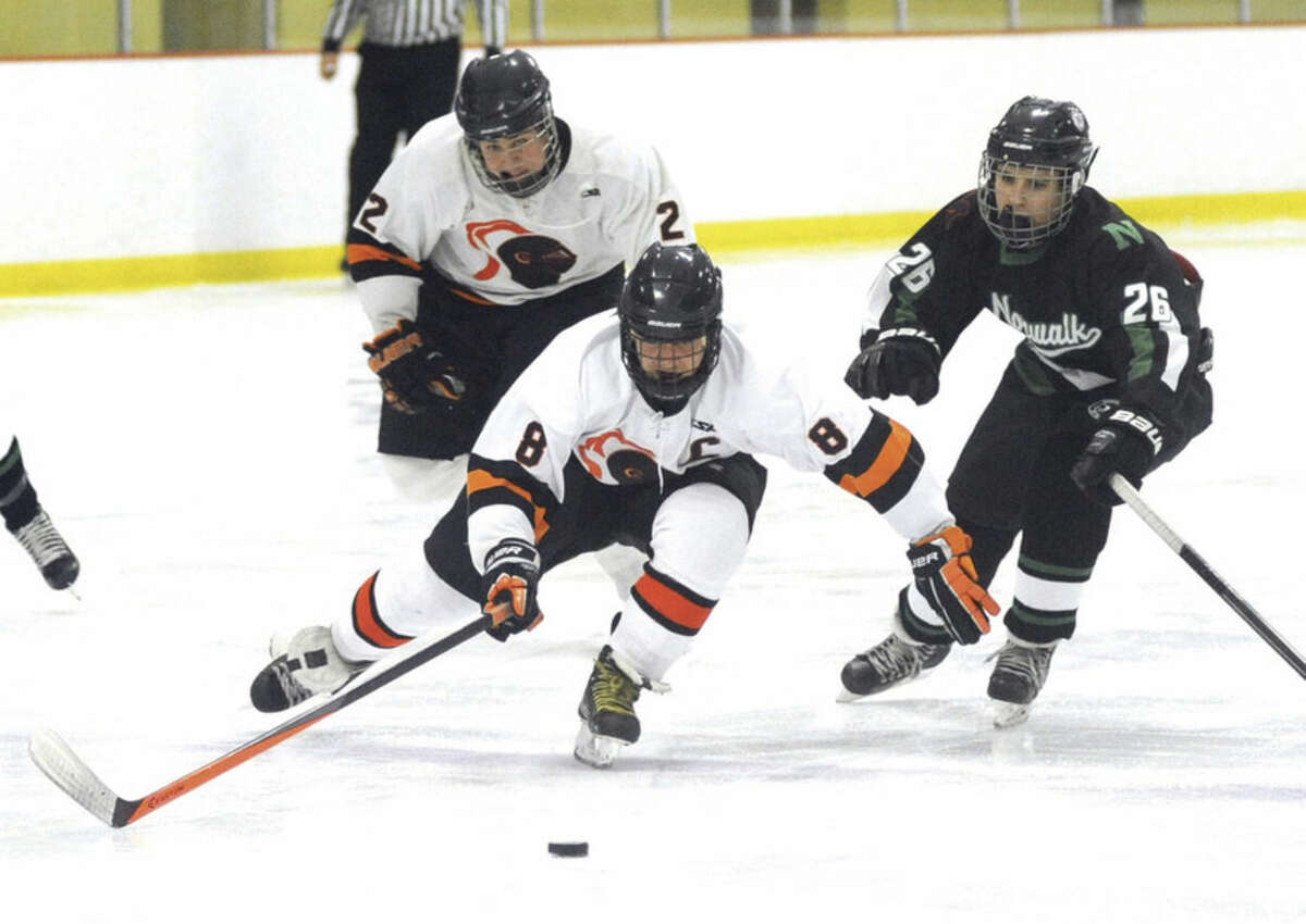 Hour photo/John Nash Stamford's Zach Rood (8) plays the puck before Norwalk-McMahon's Joe Laychak (26) can get to it as the Black Knights' Matt Tuccinardi looks on during Saturday's FCIAC hockey game in Stamford. The Black Knights won, 5-2.