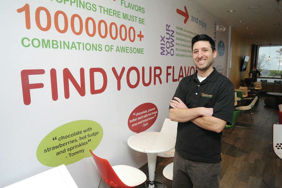 Photos by Matthew Vinci At left, Ryan Ventura, manager of Peachwave in Wilton Center, stands in the dining area of the Ridgefield Road yogurt shop, which offers 60 different flavors of the frozen dessert and an assortment of toppings.