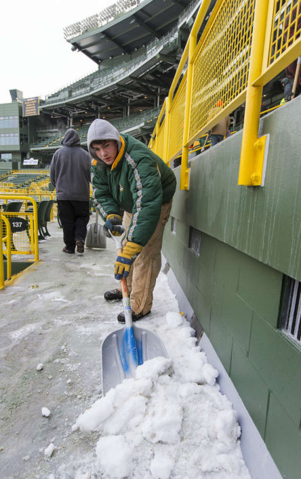 James Diedrick helps clear ice and snow from the seats at Lambeau Field on Friday, Jan. 3, 2014, in Green Bay, Wis., in preparation for Sunday's NFL football wild-card playoff game between the Green Bay Packers and San Francisco 49ers. (AP Photo/Mike Roemer)