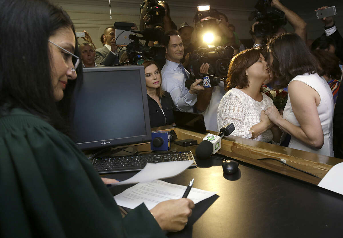 Catherina Pareto, right, and Karla Arguello, second from right, kiss after they were married by Circuit Court Judge Sarah Zabel, left, Monday, Jan. 5, 2015, in Miami. Zabel provided a jump-start Monday to Florida's entry as the 36th state where gays and lesbians can legally marry, saying she saw no reason why same-sex couples couldn't immediately get their licenses in Miami-Dade County ahead of a midnight launch statewide. (AP Photo/Wilfredo Lee)