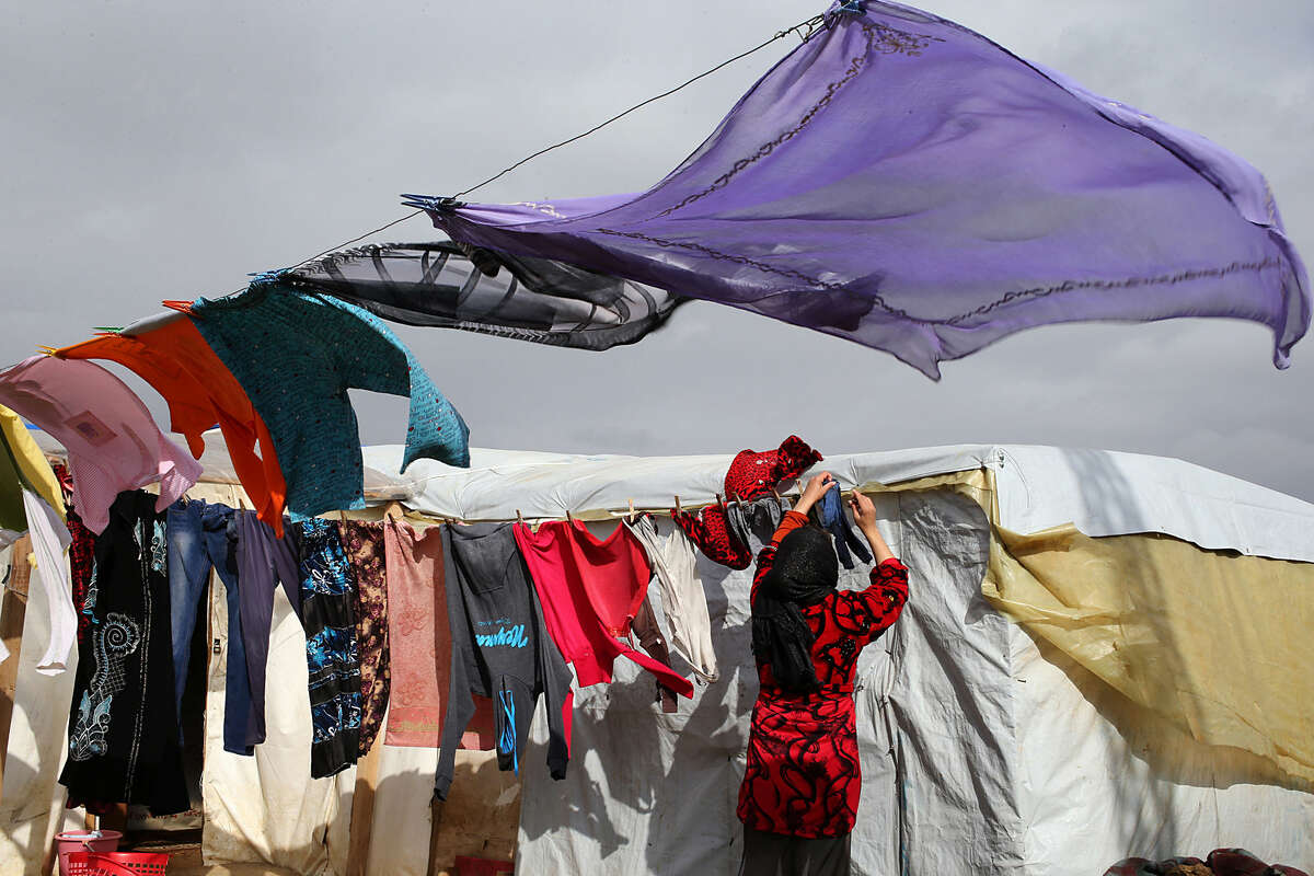 A Syrian refugee hangs her laundry at a camp in Deir Zannoun village, Bekaa valley, Lebanon, Tuesday, Jan. 6, 2015. A snow storm is expected to hit Lebanon affecting Syrian refugees, many of whom live in tents without heating. The government estimates there are about 1.5 million Syrians in Lebanon, about one-quarter of the total population. (AP Photo/Hussein Malla)
