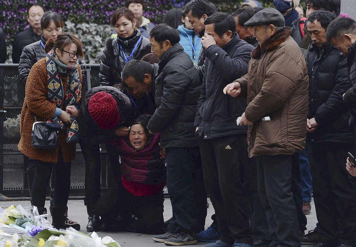A woman, third from left, grieves as she is comforted by other relatives of a New Year's Eve stampede victim at the site of the tragic accident in Shanghai, China Tuesday, Jan. 6, 2015. Some wailed and some staggered with grief as the relatives of the 36 people killed in the stampede visited the disaster site Tuesday for seventh-day commemorations that are a revered ritual in China. (AP Photo) CHINA OUT