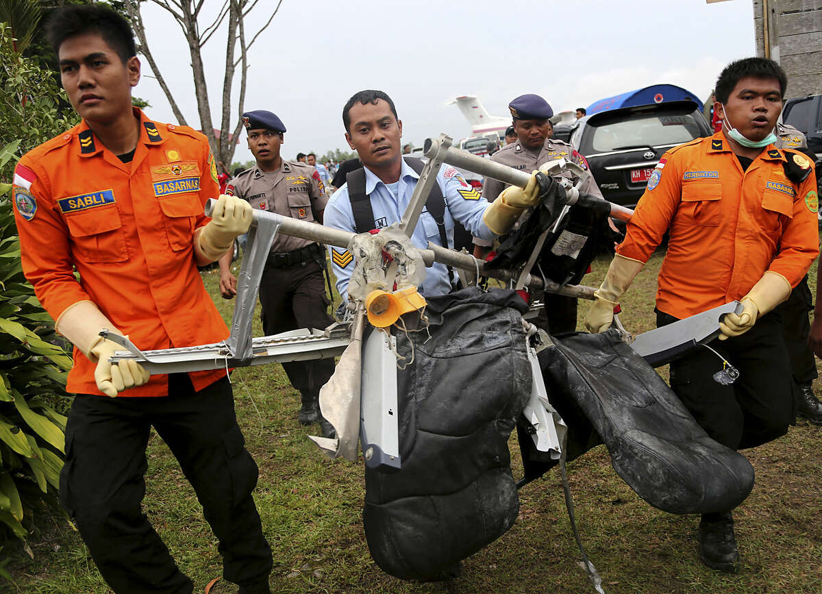 National Search and Rescue Agency personnel carry the seats of AirAsia Flight 8501 after being airlifted by a U.S. Navy helicopter, at the airport in Pangkalan Bun, Indonesia, Monday, Jan. 5, 2015. At least five ships with equipment that can detect pings emitted by flight data and cockpit voice recorders are on station and the weather has improved in the search for the AirAsia jet that crashed a week ago. (AP Photo/Tatan Syuflana)