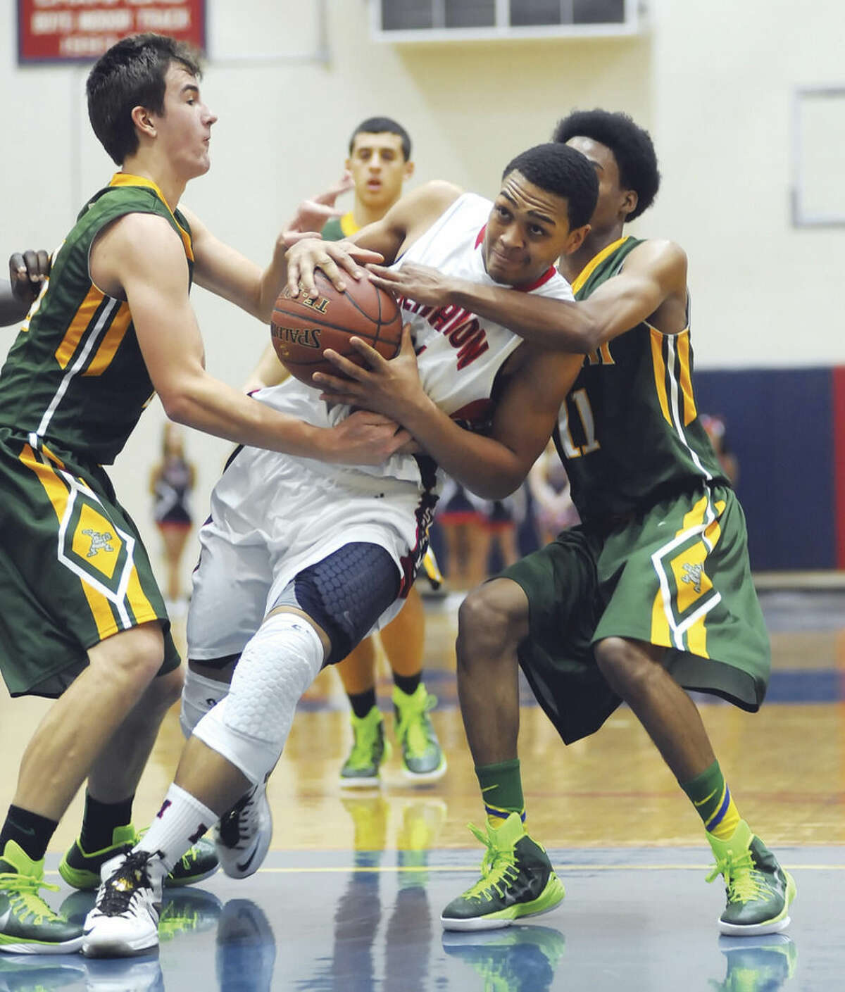 Hour photo/John Nash Brien McMahon's Timmy Hinton Jr., center, is fouled by either one or two Trinity Catholic players during the first quarter of Friday's game at King-Kehoe Gym in Norwalk.