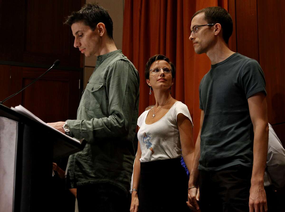 Josh Fattal, left, addresses reporters as Shane Bauer, right, holds hands with Sarah Shourd, his fiance, fellow hiker and captive, Sunday, Sept. 25, 2011 in New York. The two men were released last week after being held for espionage in an Iranian jail for almost two years. (AP Photo/Craig Ruttle)