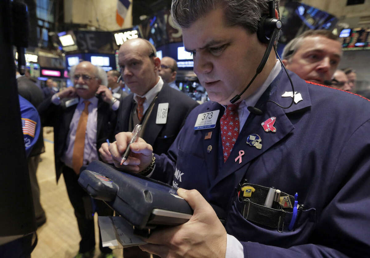 John Panin, foreground right, works with fellow traders on the floor of the New York Stock Exchange Monday, Jan. 12, 2015. Stocks are moving lower in early trading, led by a decline in energy stocks as the price of oil falls again. (AP Photo/Richard Drew)
