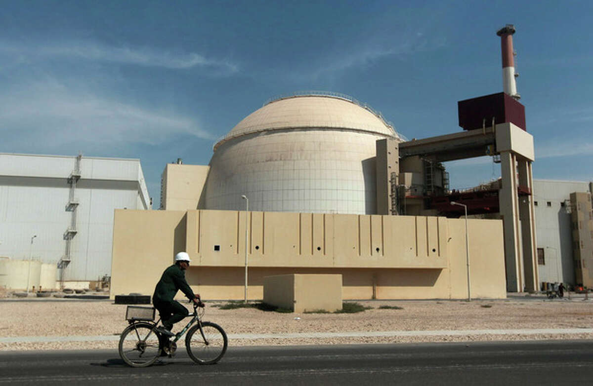 FILE - In this Oct. 26, 2010 file photo, a worker rides a bicycle in front of the reactor building of the Bushehr nuclear power plant, just outside the southern city of Bushehr. Iran and six world powers have agreed on how to implement a nuclear deal struck in November, with its terms starting from Jan. 20, officials announced Sunday. (AP Photo/Mehr News Agency, Majid Asgaripour, File)