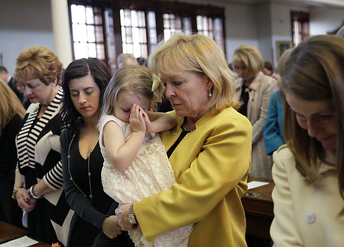 Texas State Rep. Myra Crownover, R-Denton, prays as she holds her granddaughter Claire Crownover during the opening day of the Texas Legislative session, Tuesday, Jan. 13, 2015, in Austin, Texas. (AP Photo/Eric Gay)