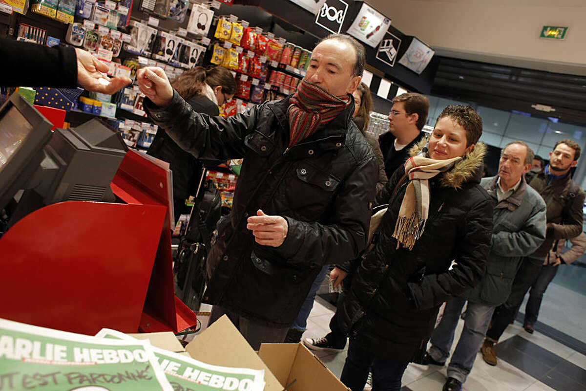 People queue up to buy the latest issue of Charlie Hebdo newspaper at a newsstand in Paris, Wednesday, Jan. 14, 2015. In an emotional act of defiance, Charlie Hebdo resurrected its irreverent and often provocative newspaper, featuring a caricature of the Prophet Muhammad on the cover that drew immediate criticism and threats of more violence. (AP Photo/Christophe Ena)