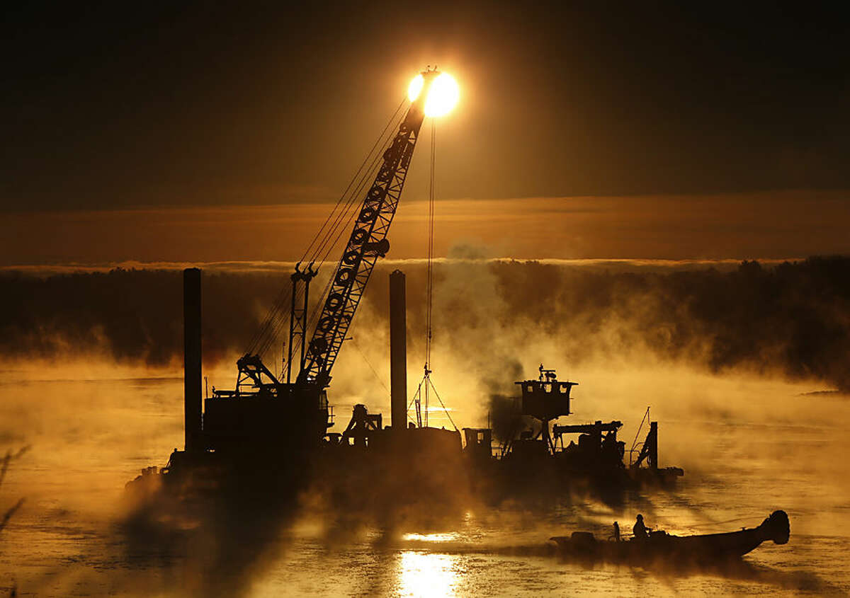 Arctic sea smoke rises on the Royal River in Yarmouth, Maine, as a worker uses a push boat to break ice forming around a dredging operation, Wednesday morning, Jan 14, 2015. The temperature at sunrise was minus 8 degrees. Sea smoke occurs when extremely cold air passes over warmer water. (AP Photo/Robert F. Bukaty)