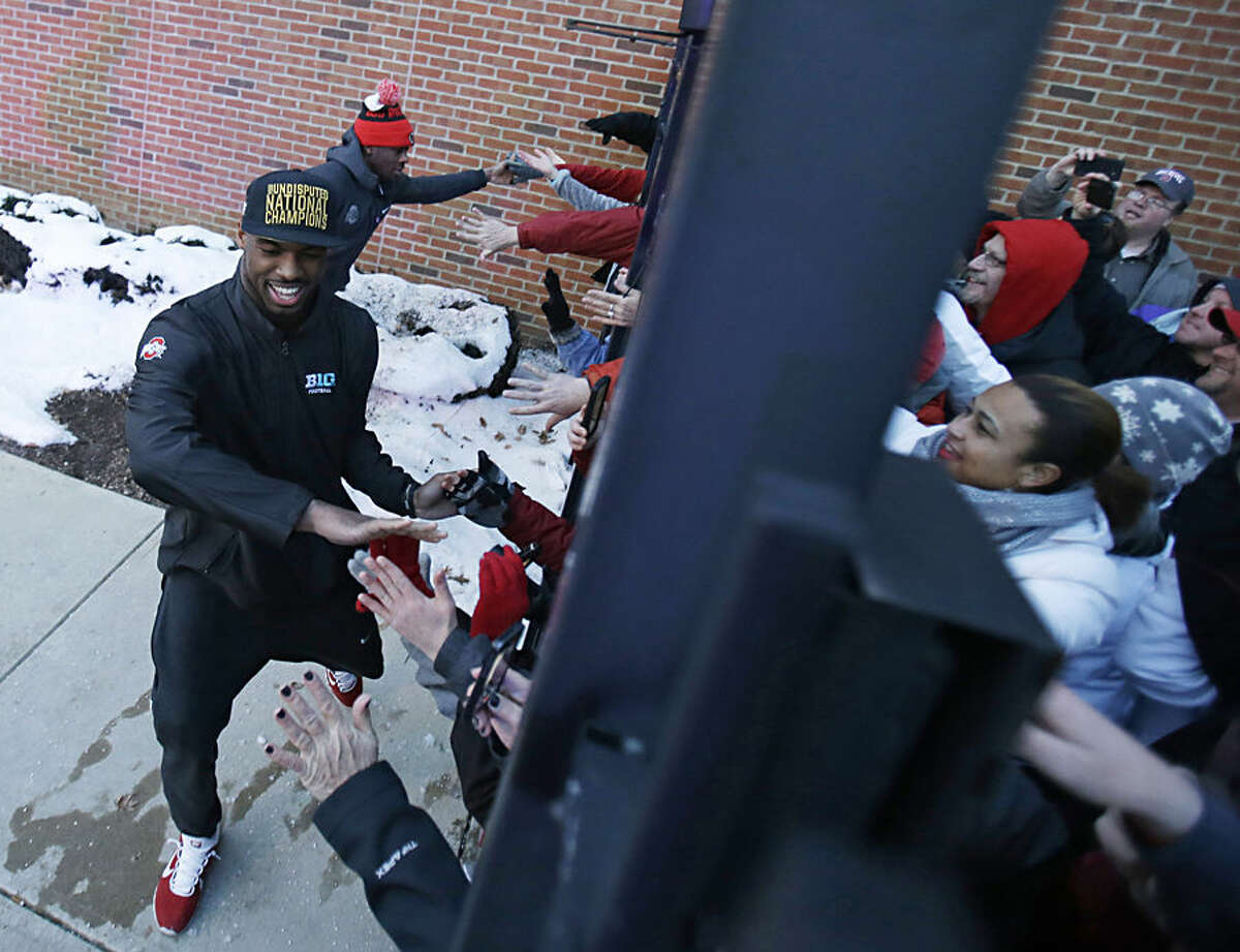 Ohio State football players high-five fans outside the Woody Hayes Athletic Center on The Ohio State University campus Tuesday, Jan. 13, 2015, in Columbus, Ohio. Ohio State defeated Oregon 42-20 in the National Championship football game. (AP Photo/Tony Dejak)