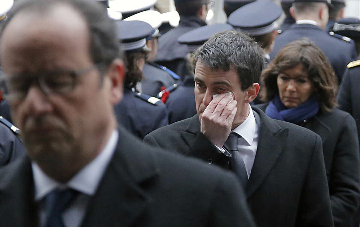 Prime Minister Manuel Valls, center, dries his tears, next to French President Francois Hollande, left, and Paris Mayor Anne Hidalgo during a ceremony to pay tribute to the three police officers killed in the attacks, in Paris, France, Tuesday, Jan. 13, 2015. Police officers Ahmed Merabet, 40, Franck Brinsolaro, 49, were killed during the attacks at Charlie Hebdo, and Clarissa Jean-Philippe killed in Montrouge last week. (AP Photo/Francois Mori, pool)