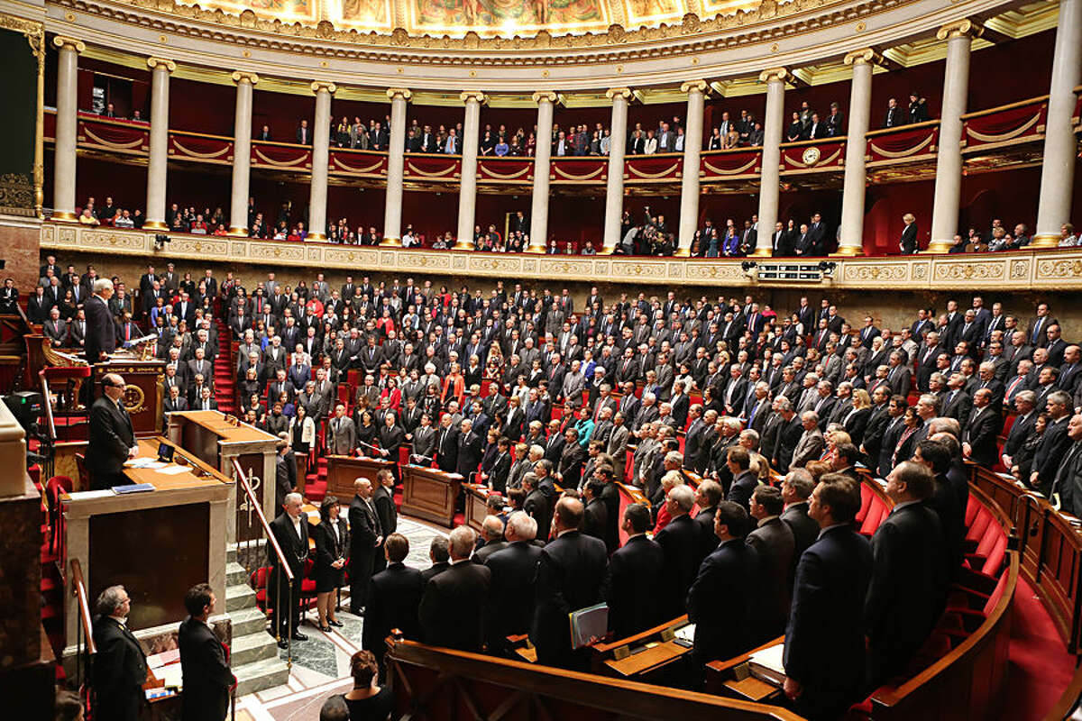 Members of the French government and deputies stand as they observe a minute of silence in homage of the 17 victims of last week terrorist attacks, at the French national Assembly in Paris, Tuesday Jan. 13, 2015. (AP Photo/Remy de la Mauviniere)
