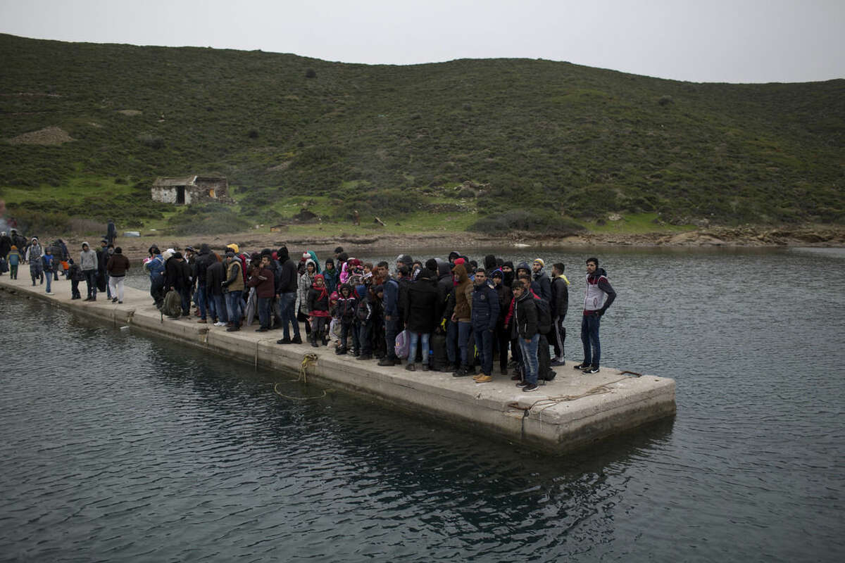 In this photo taken on Wednesday, Jan. 20, 2016, refugees and migrants who have arrived from Turkey at the shore of the deserted Greek island of Pasas wait the for the Coast Guard to transport them to Oinousses island. By morning, 283 people, including dozens of children, a disabled elderly woman and an amputee await rescue. Hour after hour, by night and by day, Greek coast guard patrol and lifeboats, reinforced by vessels from the European Union’s border agency Frontex, ply the waters of the eastern Aegean Sea along the frontier with Turkey, on the lookout for people being smuggled onto the shores of Greek islands - the frontline of Europe’s massive refugee crisis. (AP Photo/Petros Giannakouris)
