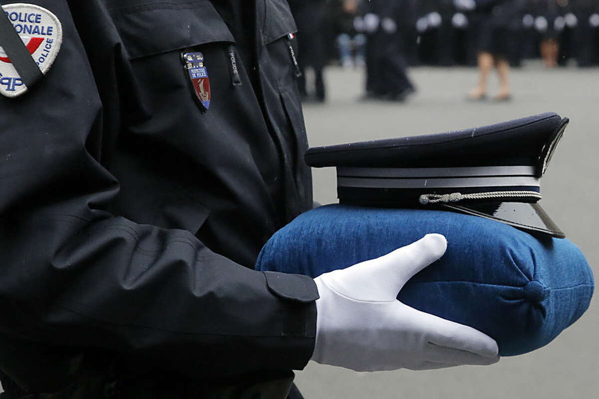 A French police officer holds the hat of late police officer Ahmed Merabet during a ceremony to pay tribute to the three police officers killed in the attacks, in Paris, France, Tuesday, Jan. 13, 2015. Police officers Ahmed Merabet, 40, Franck Brinsolaro, 49, were killed during the attacks at Charlie Hebdo, and Clarissa Jean-Philippe killed in Montrouge last week. (AP Photo/Francois Mori, pool)