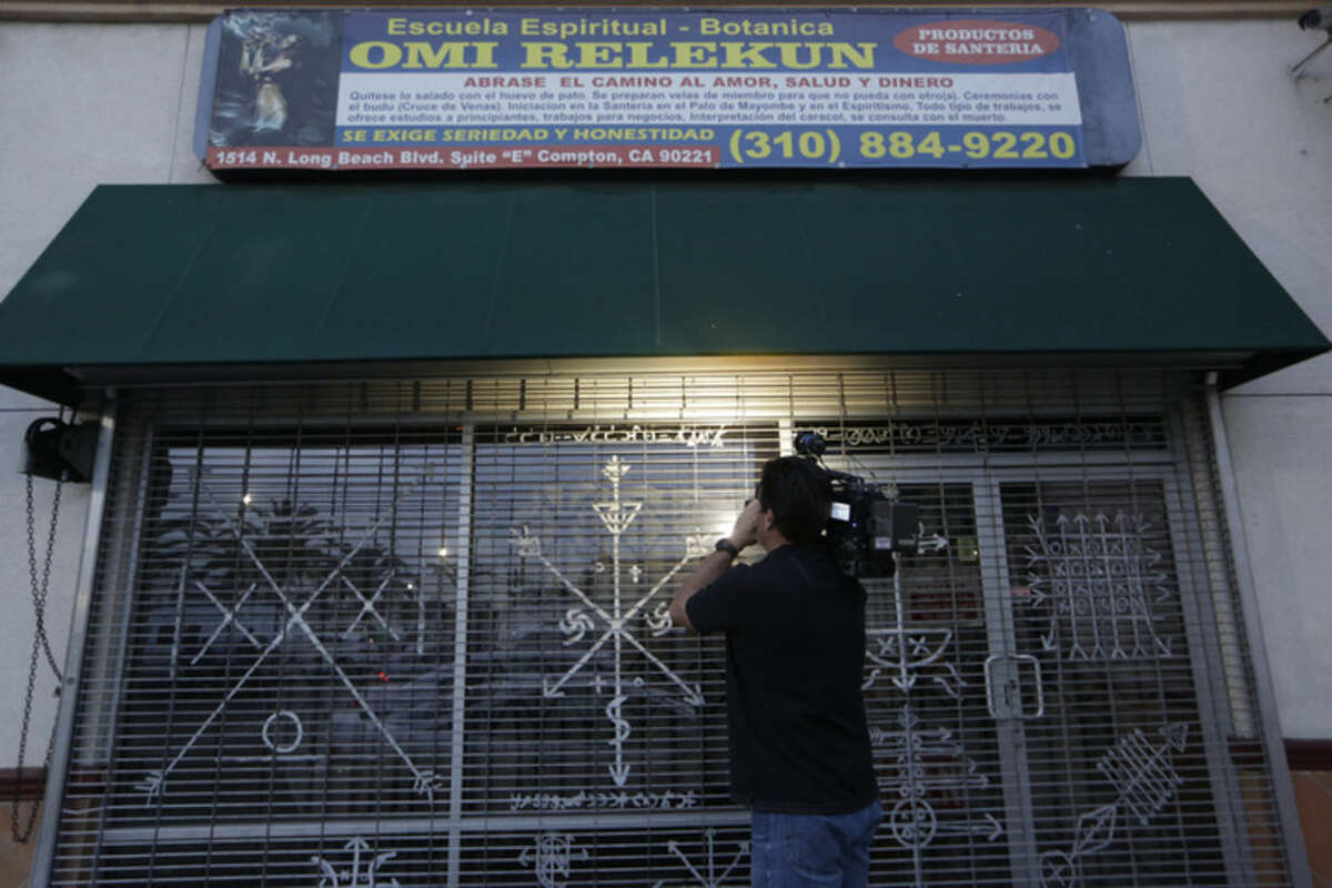 A news television cameraman, left, tapes "Santeria" motifs decorating the exterior window of a botanica called Omi Relekun in Compton, Calif., Friday Jan. 22, 2016. L.A. County sheriff’s Capt. Steve Katz says deputies responded to the shop that sells spiritual items after a woman complained of animal cruelty. Katz says they found a skull inside a pot and eight other pots that may also contain skulls. Katz says there's no evidence of a homicide and that it appears the skull may have been purchased from a legal source and was being used for a religious ceremony. He says it's unclear whether animal remains were found. (AP Photo/Damian Dovarganes)