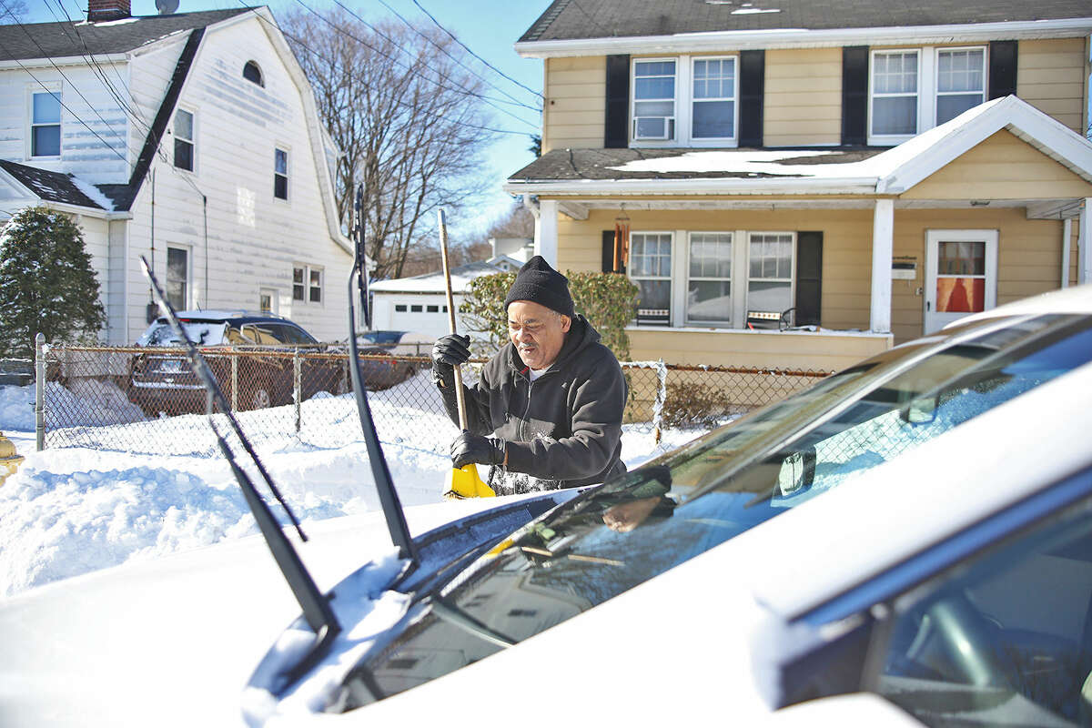 Henry Hayes brushes the snow off of his car on Loundsbury Avenue in Norwalk after Winter Storm Jonas Sunday morning. Hour Photo / Danielle Calloway