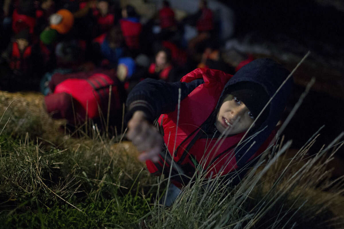 In this photo taken on Wednesday, Jan. 20, 2016, an Afghan boy asks for help to climb a rock leading to the main road, after arriving on a dinghy from the Turkish coast to the Greek island of Chios. Refugees and Migrants are risking their lives in a quest for safety and a better future in Europe. Hour after hour, by night and by day, Greek coast guard patrol and lifeboats, reinforced by vessels from the European Union’s border agency Frontex, ply the waters of the eastern Aegean Sea along the frontier with Turkey, on the lookout for people being smuggled onto the shores of Greek islands - the frontline of Europe’s massive refugee crisis. (AP Photo/Petros Giannakouris)