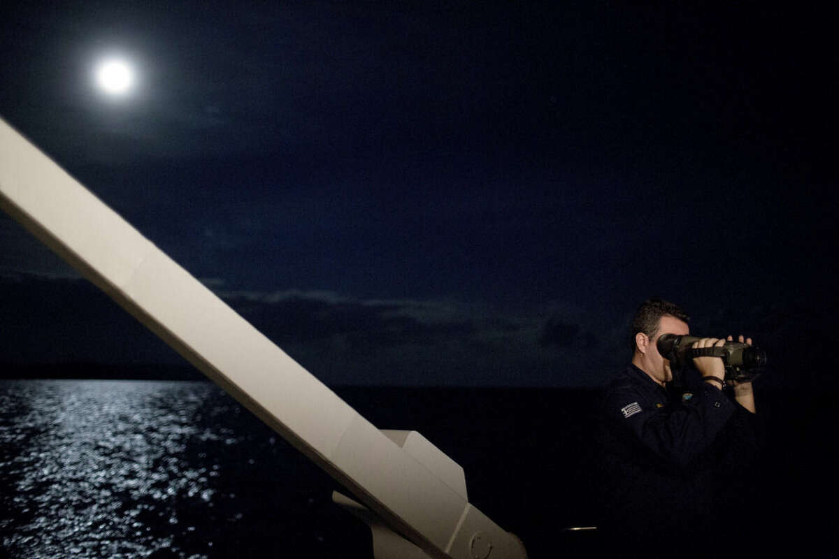 In this photo taken on Wednesday, Jan. 20, 2016, a Greek Coast Guard officer looks through night vision binoculars during a patrol at the Aegean sea near the Greek island of Chios. Greek coast guard patrol vessels and lifeboats reinforced by the European Union’s border agency Frontex ply the waters of the eastern Aegean Sea along the frontier with Turkey, on the lookout for people being smuggled onto Greek islands, the frontline of Europe’s massive refugee crisis. (AP Photo/Petros Giannakouris)