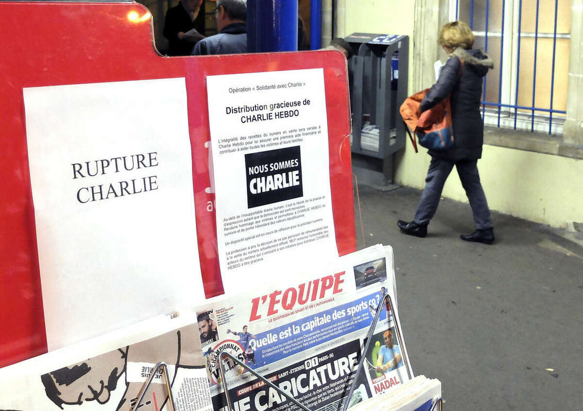 A woman walks past a newsstand with a sign stating "Charlie Hebdo sold out" at the Ville d'Avray train station, west of Paris, France, Wednesday, Jan. 14, 2015. Charlie Hebdo's defiant new issue sold out before dawn around Paris on Wednesday, with scuffles at kiosks over dwindling copies of the paper fronting the Prophet Muhammad. (AP Photo/Bertrand Combaldieu)