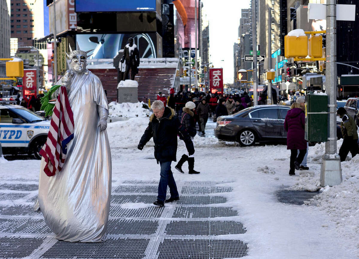 A costumed character, along with pedestrians, navigate sometimes slippery conditions in New York's Times Square Sunday, Jan. 24, 2016, in the wake of a storm that dumped heavy snow along the East Coast. (AP Photo/Craig Ruttle)