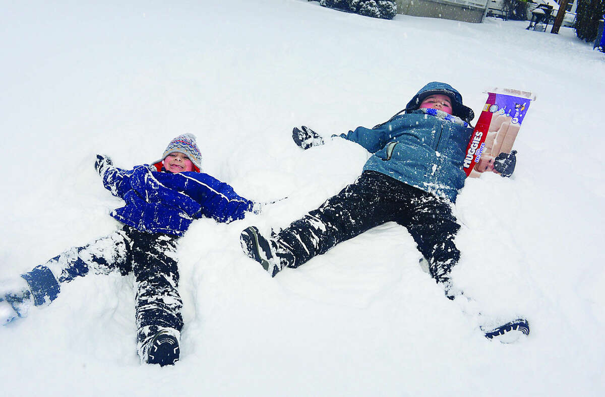 Hour photo / Erik Trautmann Brothers Alex and David Mandujano make snow angels on their front lawn during Snowstorm Jonas on Saturday afternoon.