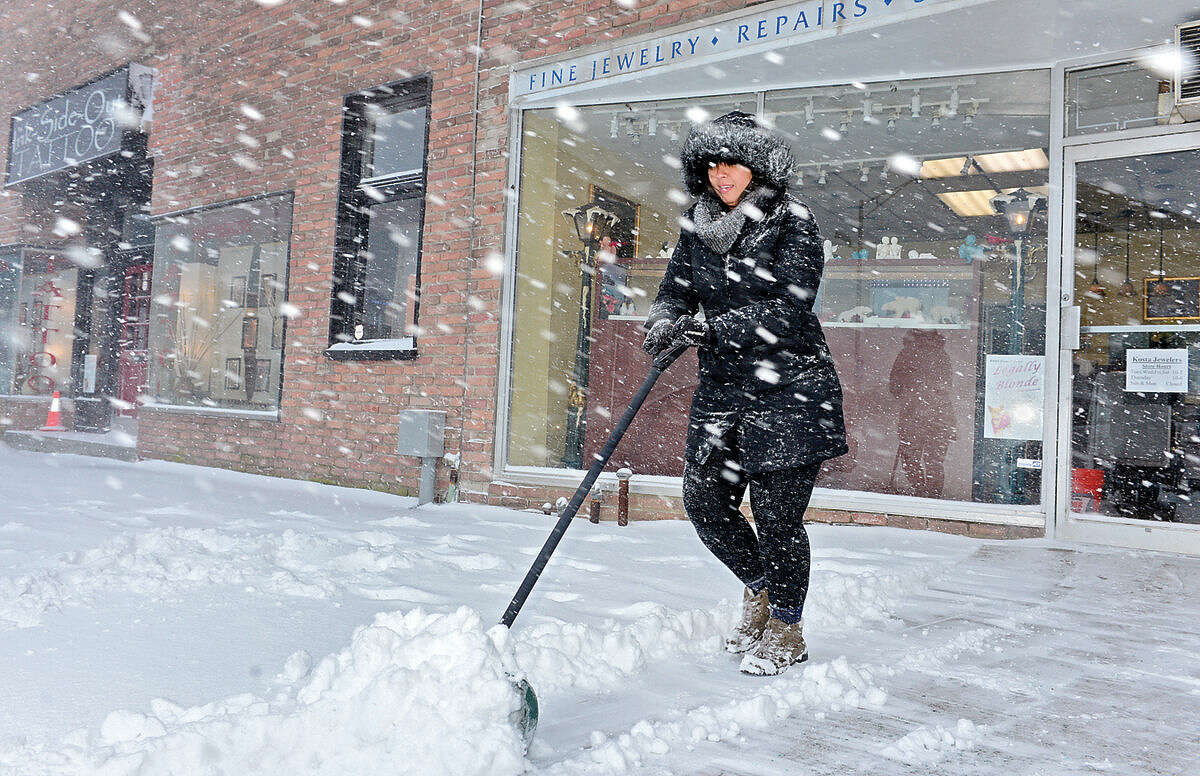 Hour photo / Erik Trautmann Priscilla Yoshida shovels the walk along Wall St as Snowstorm Jonas moves through the area Saturday.