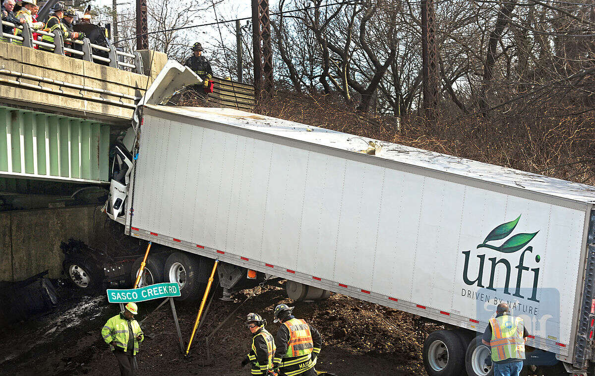Hour photo / Erik Trautmann Emergency personnel try to free a tractor trailer after in went off the roadway and crashed into the bridge abutment on I-95 Northbound near exit 19 Friday.