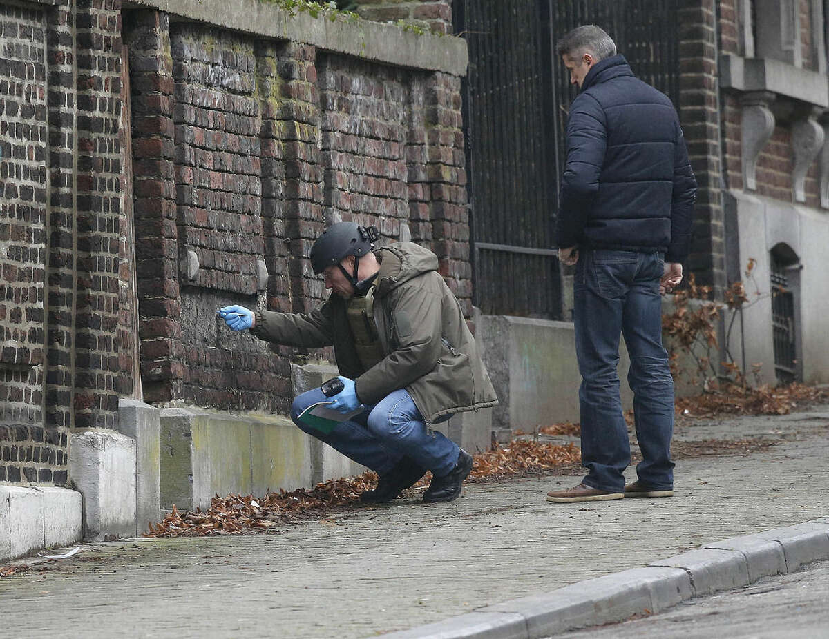 Belgian police officers examine a wall in a street in Verviers, Belgium, Friday, Jan. 16, 2015. The street was blocked after security forces took part in anti-terrorist raids in Verviers, eastern Belgium on Thursday in which two people were killed and one arrested during a shootout in an anti-terrorist operation in the eastern city of Verviers. (AP Photo/Frank Augstein)