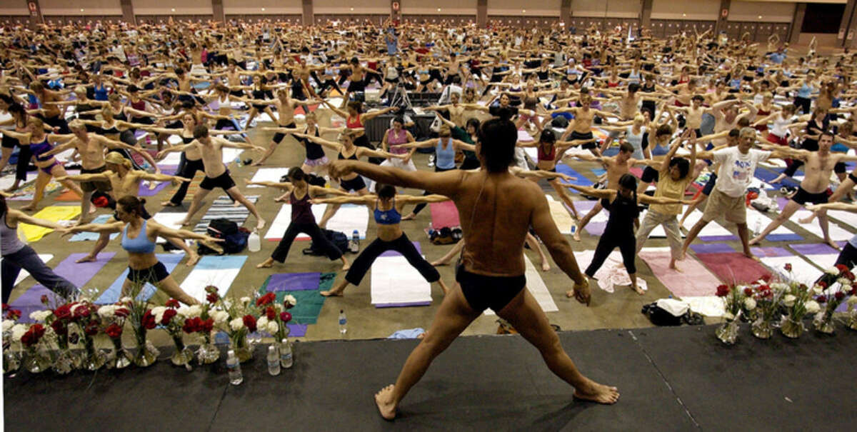 FILE - In this Sept. 27, 2003, file photo, Bikram Choudhury, front, founder of the Yoga College of India and creator and producer of Yoga Expo 2003, leads what organizers hope will be the world's largest yoga class at the Los Angeles Convention Center. A Los Angeles jury on Monday, Jan. 25, 2016, ordered Choudhury to pay more than $900,000 in compensatory damages after finding he had subjected a lawyer to harassment and retaliation. (AP Photo/Reed Saxon, File)