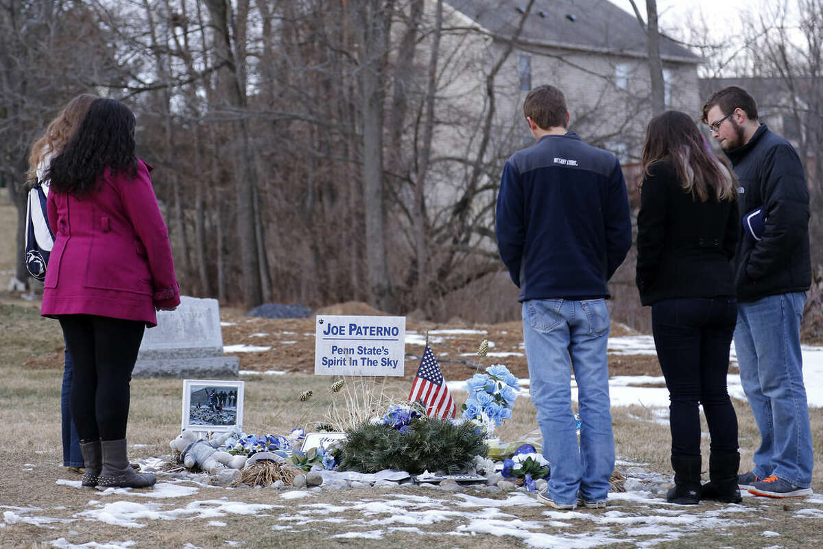 A group of Penn State students gather around the grave of the late Penn State football coach Joe Paterno, Friday, Jan. 16, 2015 in State College, Pa. The NCAA announced a settlement Friday with Penn State that will give the school back 112 wins wiped out during the Jerry Sandusky child molestation scandal and restore Paterno as the winningest coach (409) in major college football history. (AP Photo/Gene J. Puskar)