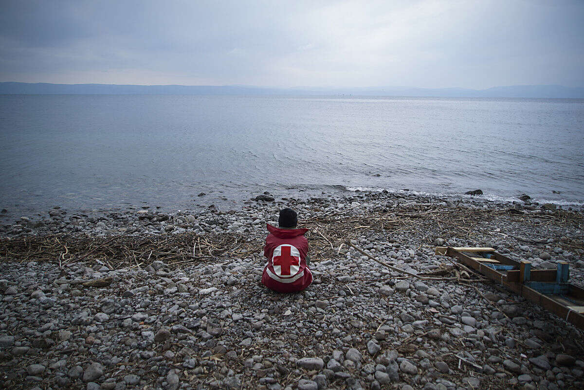A member of the Greek Red Cross waits for migrants and refugees to arrive on a beach of the Greek island of Lesbos Tuesday, Jan. 26, 2016. More than 850,000 people, most fleeing conflict in Syria and Afghanistan, entered Greece by sea in 2015, according to the UNHCR, and already in 2016, some 35,455 people have arrived despite plunging winter temperatures.(AP Photo/Mstyslav Chernov)