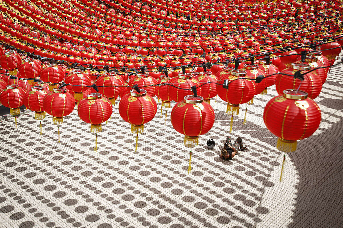 A tourist lies on the floor cast with shadows of traditional Chinese lanterns ahead of the Lunar New Year celebrations in Kuala Lumpur, Malaysia, Wednesday, Jan. 27, 2016. The Lunar New Year which falls on Feb. 8 this year marks the Year of the Monkey in the Chinese calendar. (AP Photo/Joshua Paul)