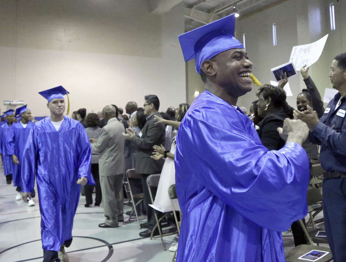 In this photo taken Dec. 12, 2014 shows inmates, in caps and gowns in the Prison Entrepreneurship Program marching toward the stage for graduation ceremonies, at the Cleveland Correctional Facility in Cleveland, Texas. The Prison Entrepreneurship Program, or PEP, is based on a philosophy that making inmates like Chavez business savvy will reduce the likelihood that they’ll end up back in prison. It emphasizes reforming behavior while also working on a broader goal of reducing the prison population. (AP Photo/Pat Sullivan)