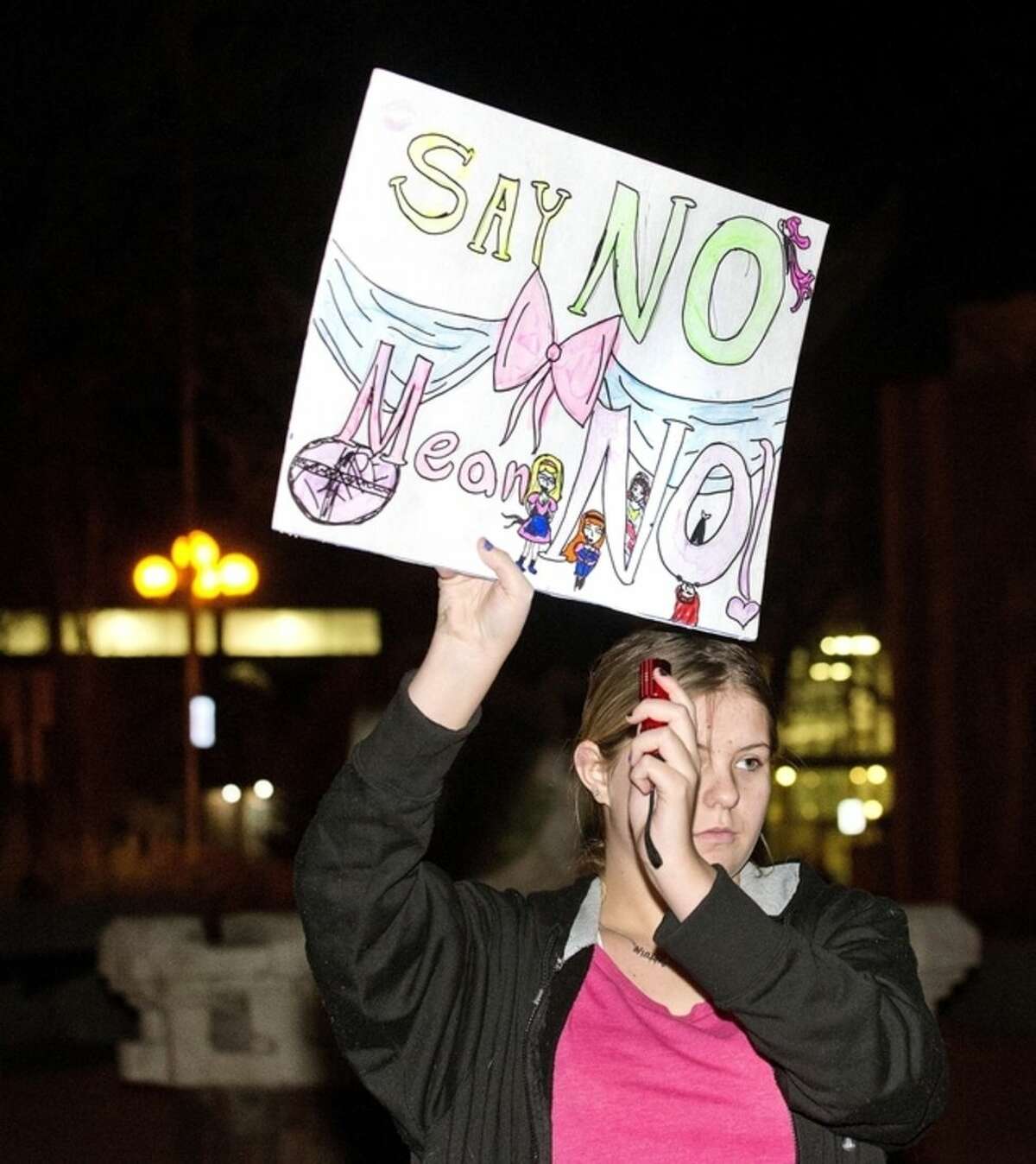 Rayla Riddick holds up a light to a sign during a protest of a Bill Cosby appearance in Pueblo, Colo., Friday, Jan. 16, 2015. A group of about 25 people gathered before the show to protest with signs and chants. (AP Photo/The Pueblo Chieftain, Chris McLean)