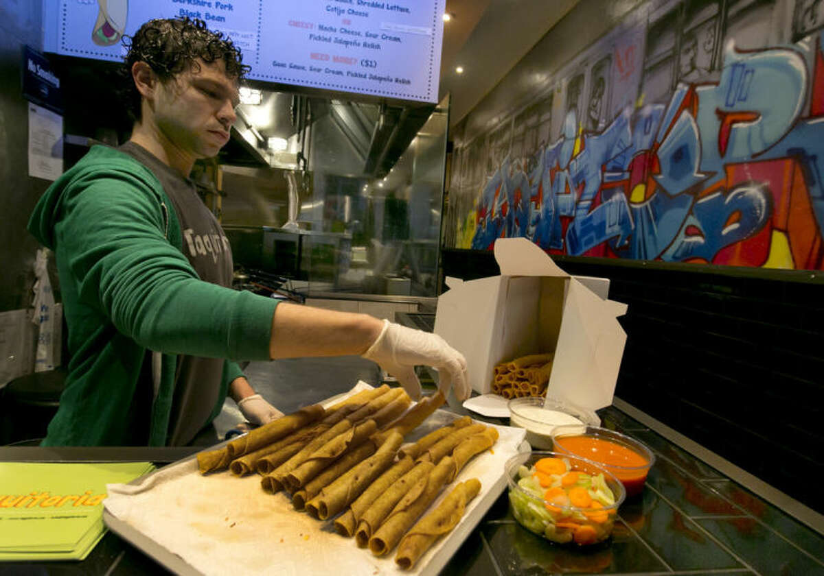 Owner and manager Brad Holtzman of Taquitoria, on New York's Lower East Side, fills a box of Buffalo chicken taquitos, Tuesday, Jan. 14, 2014. Taquitoria, a shop that serves only the deep-fried, cigar-like tortillas called taquitos, offers 40-piece boxes of the Buffalo chicken taquitos throughout football season. On Super Bowl game day they expect to do 99 percent of their business for takeout. (AP Photo/Richard Drew)