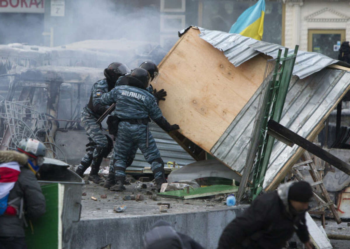 Police work to clear a barricade during unrest in central Kiev, Ukraine, Monday, Jan. 20, 2014. Protesters erected barricades from charred vehicles and other materials in central Kiev as the sound of stun grenades could be heard in the freezing air. (AP Photo/Sergei Chuzavkov)
