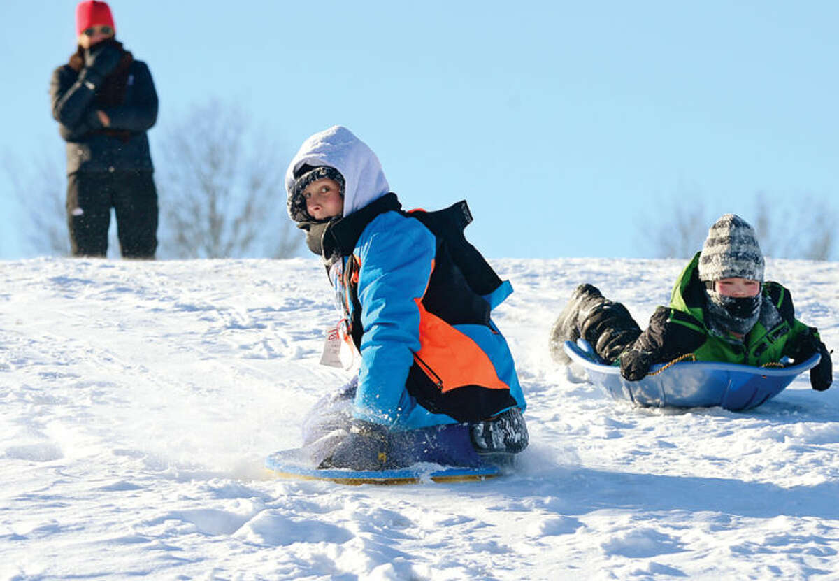 Hour photo / Erik Trautmann Christian Miller, 11, and Colin Lenskold, 10, sled at Nathan Hale Middle School following the snowstorm that left the area blanketed with snow and canceled public school in Norwalk Wednesday. 