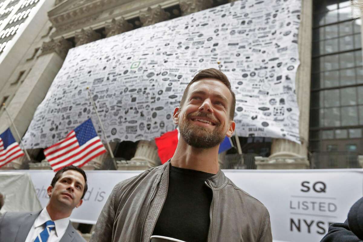 Square CEO Jack Dorsey, foreground, visits outside the New York Stock Exchange before opening bell ceremonies, Thursday, Nov. 19, 2015. Square, the 6-year-old startup known for its white, cube-shaped card readers that plug into smartphones, is surging in its first day as a publicly traded company. (AP Photo/Richard Drew)
