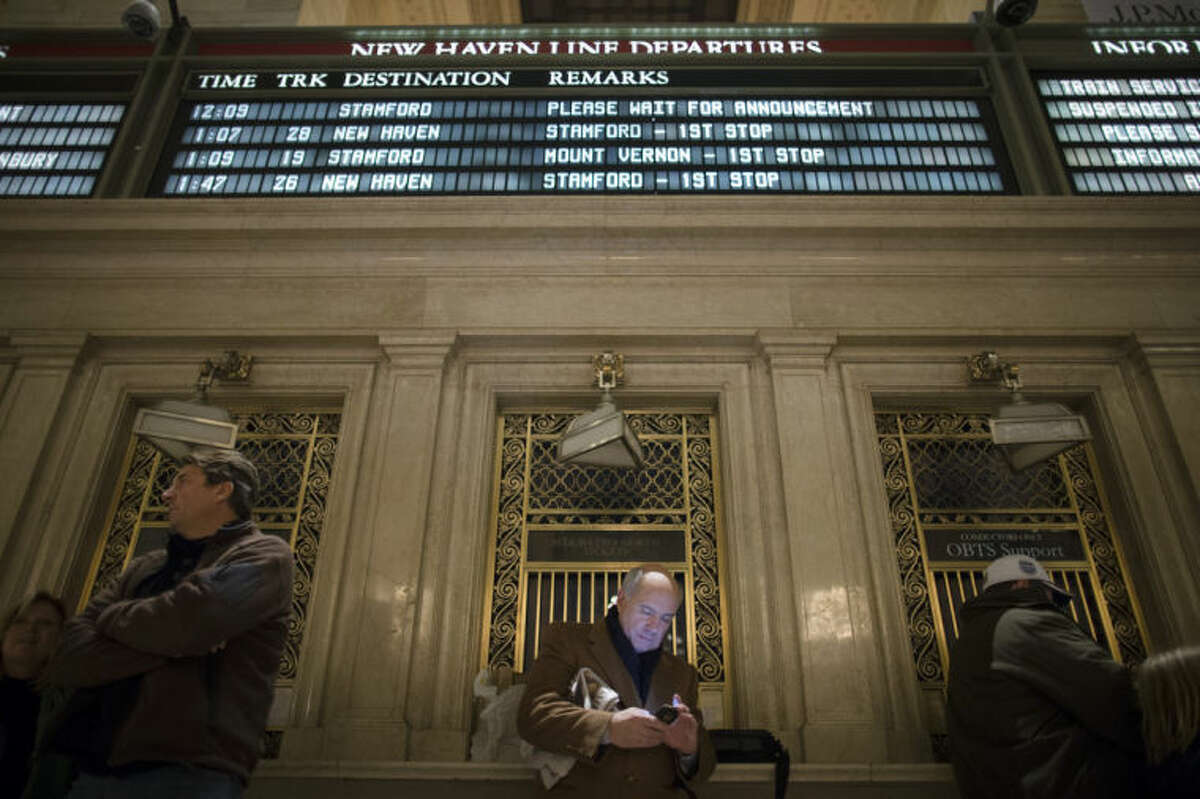 A commuter stands beneath the New Haven train line schedule display in the main hall of Grand Central Station as hundreds wait after a power problem with Metro-North Railroad's computer system caused the suspension of service on the Hudson, Harlem, and New Haven lines, Thursday, Jan. 23, 2014, in New York. Trains were brought to a halt for safety purposes while electricians worked to hook up temporary power to the computer system. Metro-North is the nation's second-busiest railroad and serves 281,000 riders a day in New York and Connecticut. (AP Photo/John Minchillo)