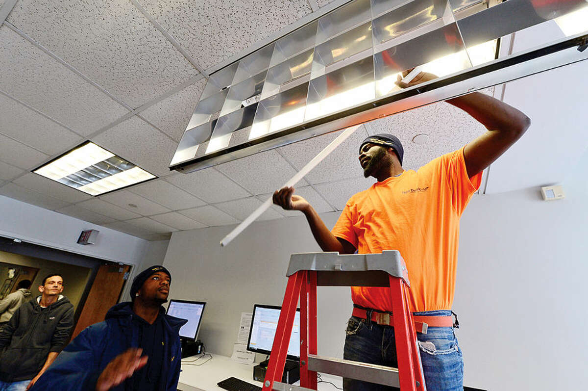 Hour photo / Erik Trautmann Michael Thompson and Andre Campbell of Taylor electric install energy efficient upgrades to light fixtures at Norwalk City Hall Friday following a press conference by Norwalk Mayor Harry Rilling and Councilman John Kydes who announced the upgrades.