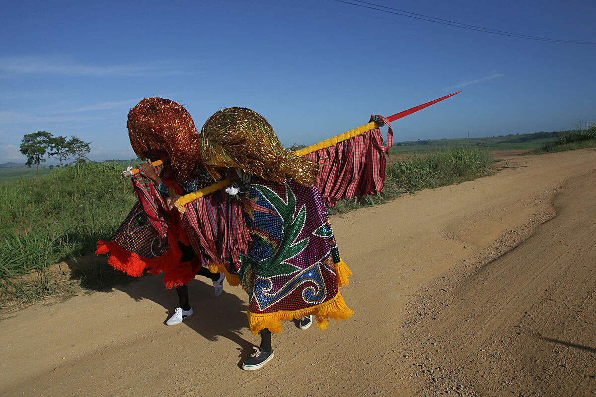 In this Feb. 7, 2016 photo, "Caboclo de Lanca," or lance-bearers, Nego Benvindo, left, and Jose Esteves, walk to town for Maracatu Carnival celebrations in Nazare da Mata, Brazil. The Afro-indigenous tradition is one of the oldest in northeastern Pernambuco state. (AP Photo/Eraldo Peres)